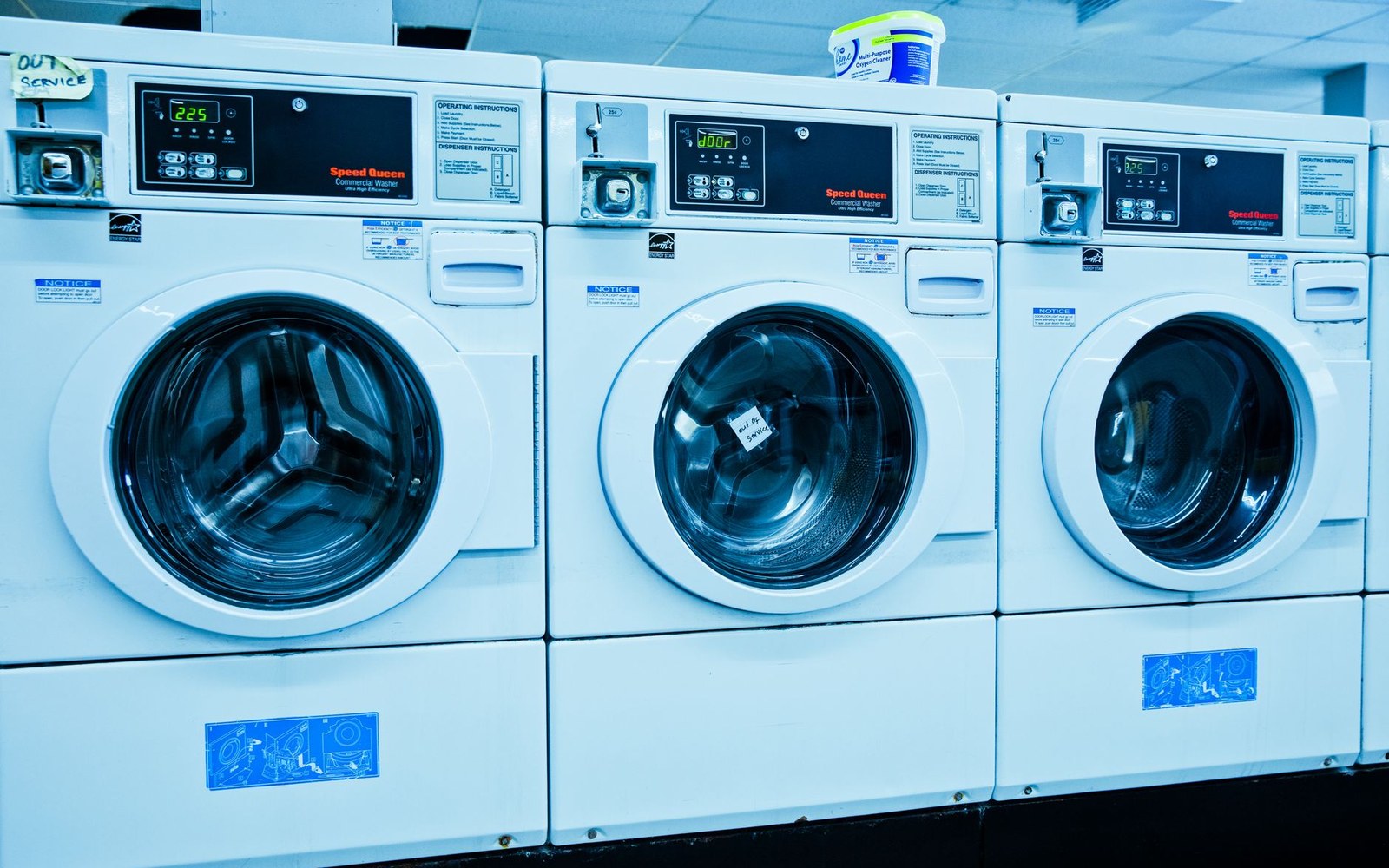 Row of coin-operated commercial washing machines with digital displays in a laundromat